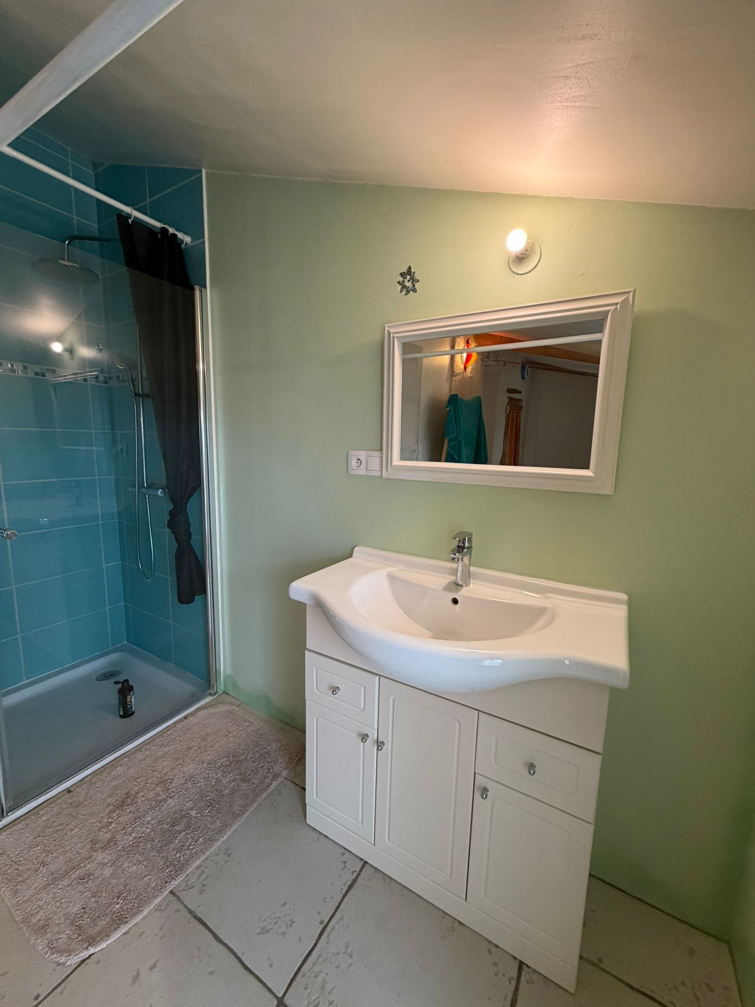 A bathroom with a shower, sink, and mirror.