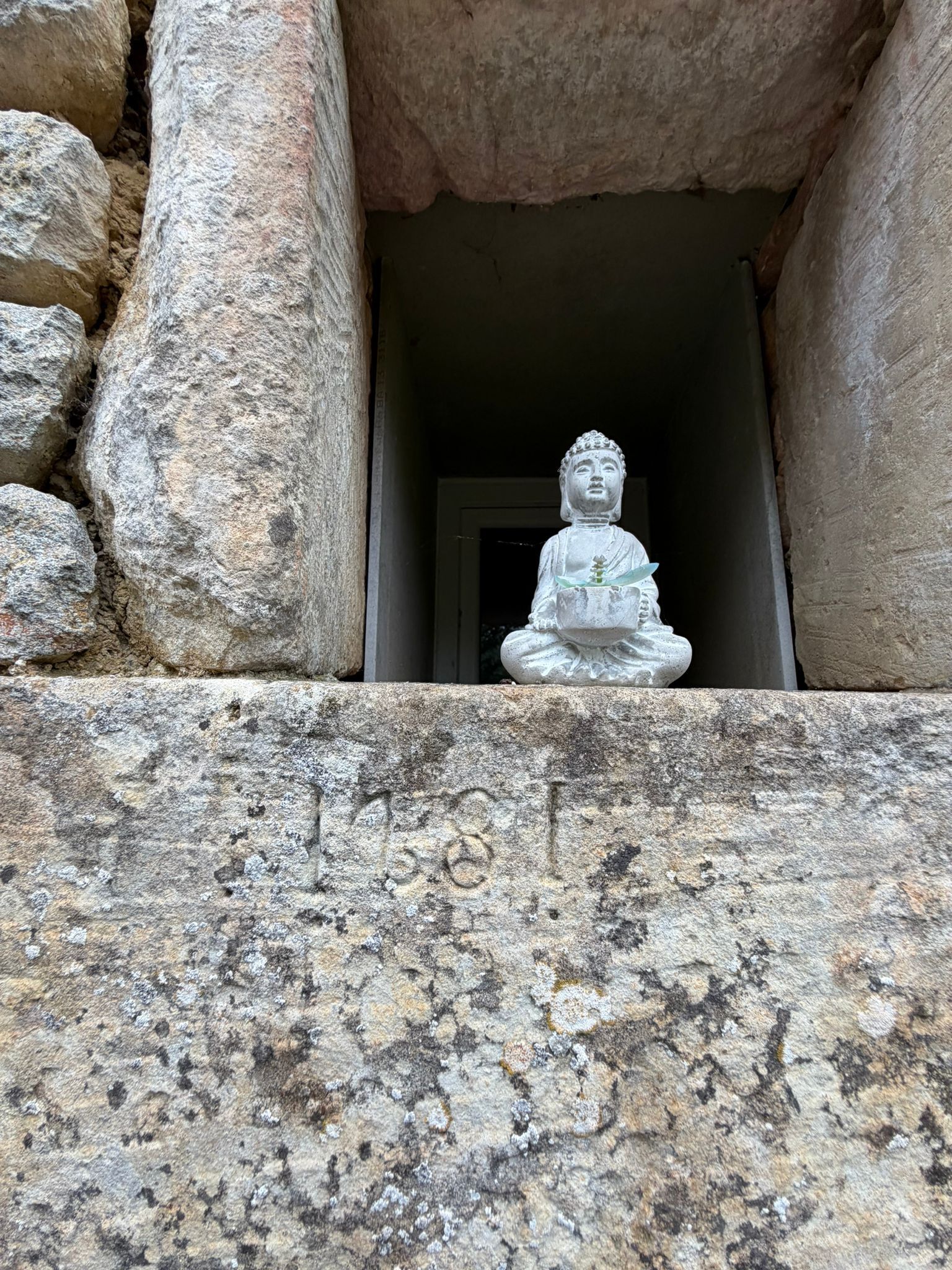 A stone Buddha statue in a niche with inscriptions.