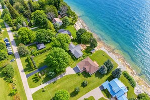 Ett flygbildsbild av ett bostadsområde vid kusten med hus, en parkeringsplats och en fri utsikt över havet.