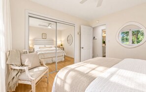 Un dormitorio con una cama grande, una silla, un espejo y una puerta que da a otra habitación.