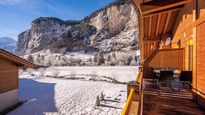 Un edificio in legno con un balcone che si affaccia su un paesaggio innevato e una montagna.