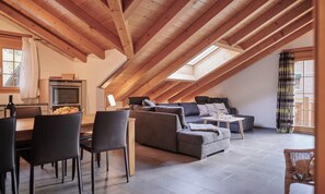 A loft-style living space with a dining area, a sofa set, and a kitchen with an oven. - SPACIOUS CHALET PENTHOUSE WITH SPECTACULAR MOUNTAIN VIEWS (Lauterbrunnen)