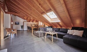 An attic living space with a dining area, a sofa, and a chair. - SPACIOUS CHALET PENTHOUSE WITH SPECTACULAR MOUNTAIN VIEWS (Lauterbrunnen)