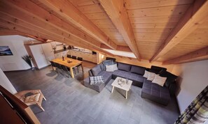 A spacious loft with a dining area, a sofa set, and a kitchen in the background. - SPACIOUS CHALET PENTHOUSE WITH SPECTACULAR MOUNTAIN VIEWS (Lauterbrunnen)