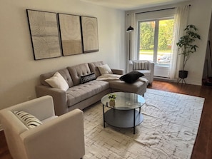 A living room with a sofa, armchair, coffee table, and a potted plant. - Condo in the National Capital (Gatineau)