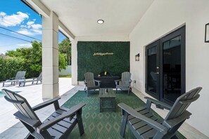A covered outdoor seating area with Adirondack chairs, a table, and a green wall with a motivational quote. - Casa Azure Family Friendly Home with Heated Pool (Miami)