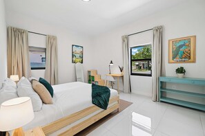 A modern hotel room with a bed, bedside table, lamp, and a view of the outdoors. - Casa Azure Family Friendly Home with Heated Pool (Miami)