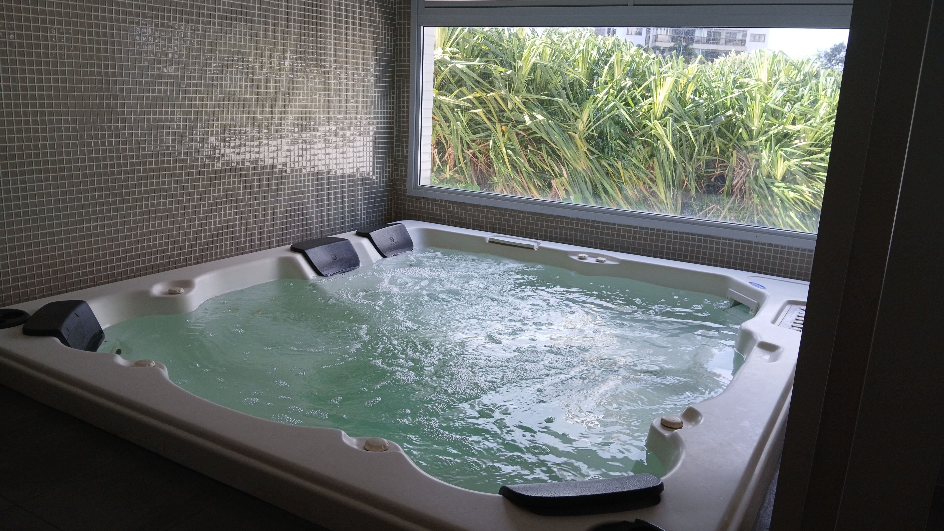 A hot tub with a view of greenery outside.