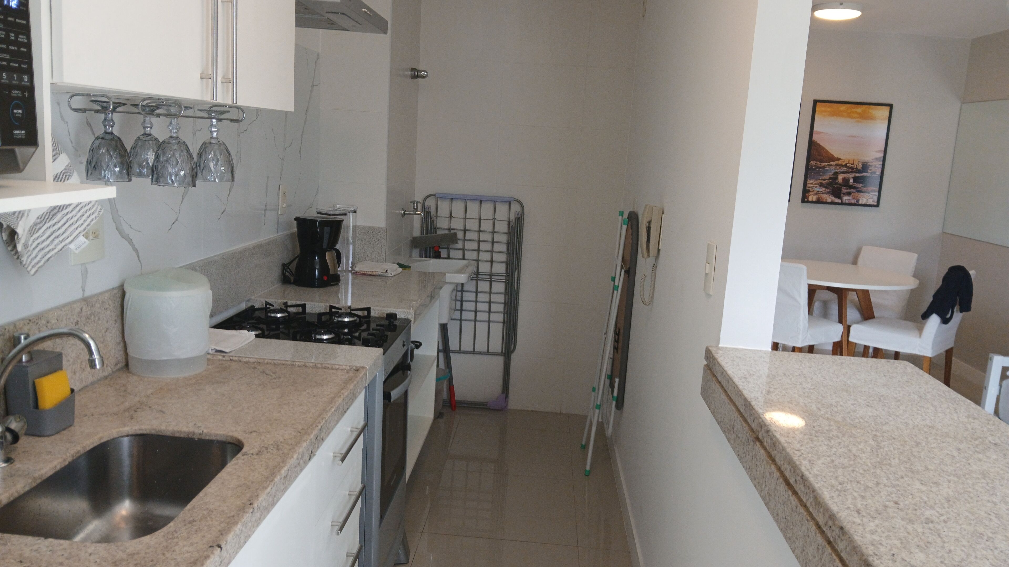 Cozinha compacta com fogão a gás, pia e cafeteira.