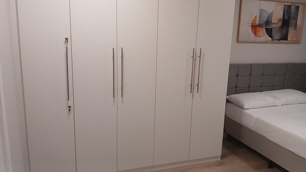 Un dormitorio con cama, armario y un cuadro en la pared.