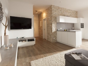 A modern living room with a flat-screen TV, a built-in entertainment unit, and a cozy seating area with a rug. - Amelie (Norderney)