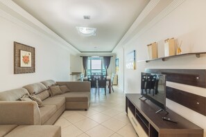 A living room with a sectional sofa, a flat-screen TV, and a dining area with chairs and a table. - Breathtaking ocean views in Porto Belo. (Porto Belo)