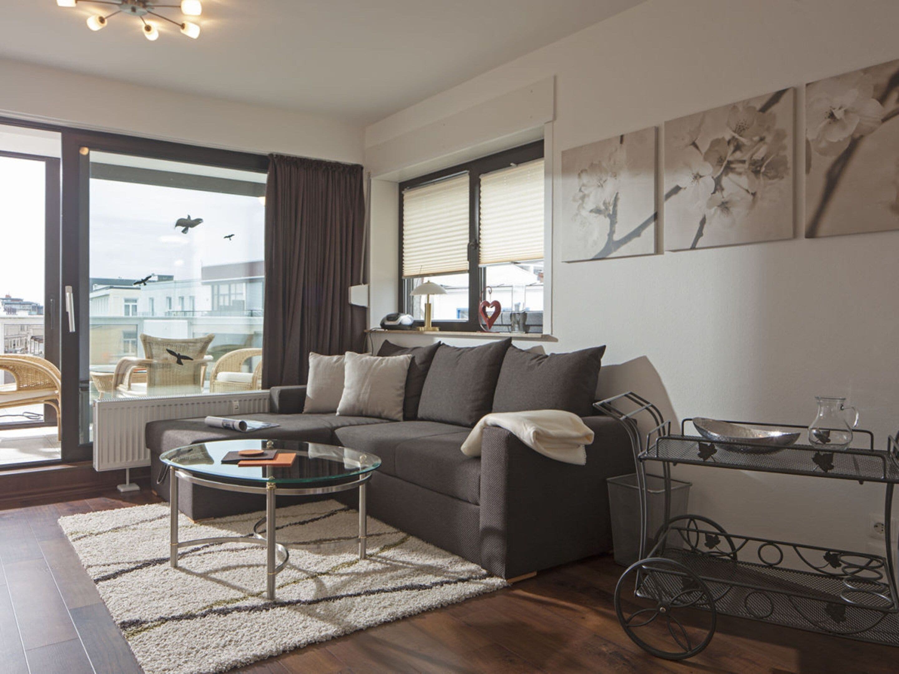 A modern living room with a sofa, a glass coffee table, and a view of the city through large windows.