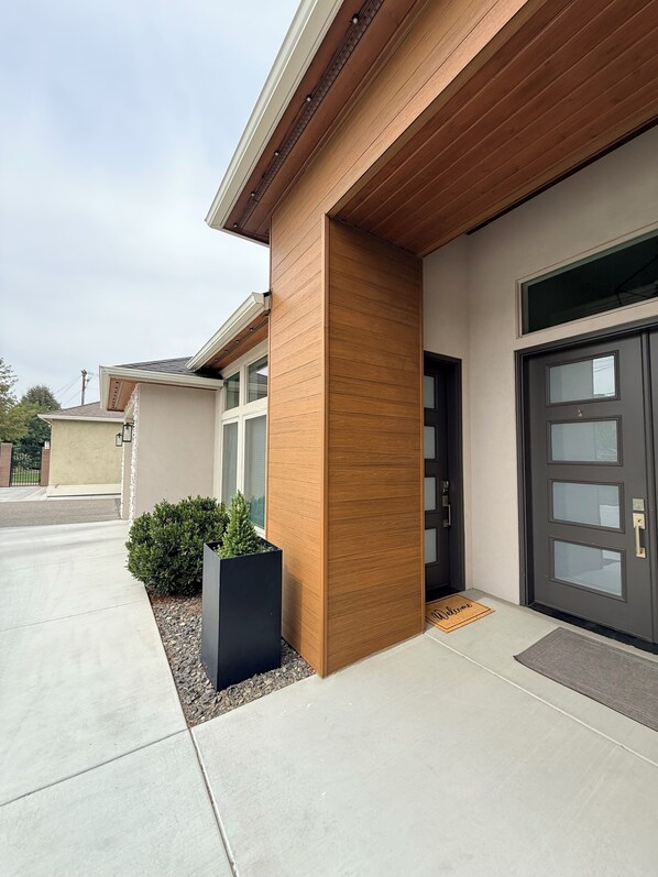 A modern building with a garage door, a welcome mat, and a small planter with greenery.