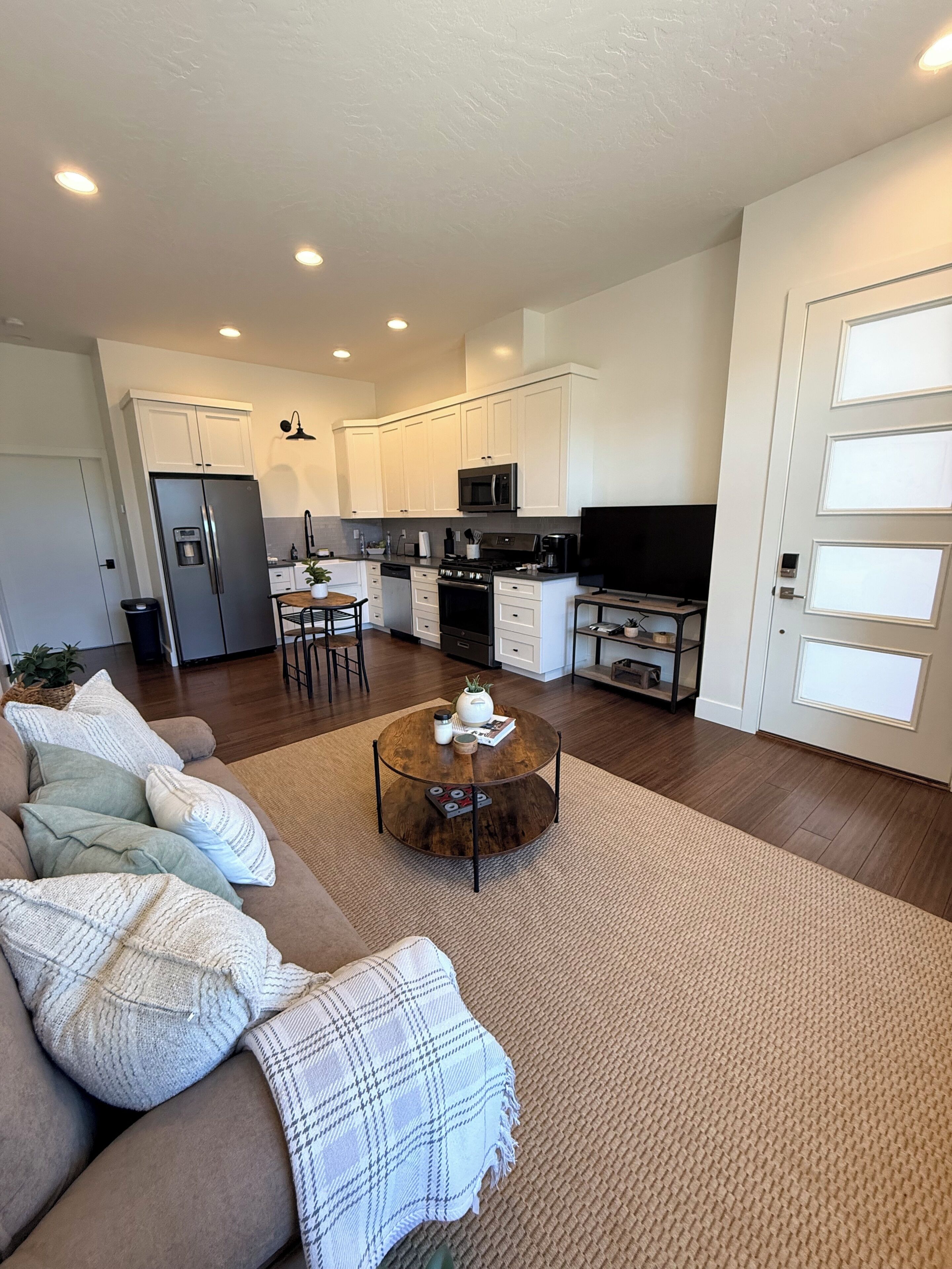 A modern living room with a sofa, coffee table, and a kitchen area in the background.