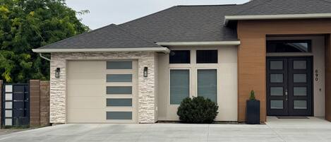 A modern two-story house with a garage, a stone facade, and a well-maintained lawn.