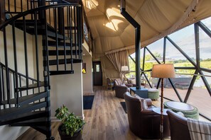 A spacious interior with a spiral staircase, wooden flooring, and a view through large windows.