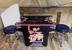 Una mesa con máquinas de videojuegos, dos taburetes y una pizarra.
