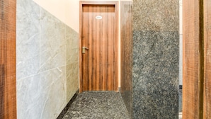A narrow hallway with a wooden door, marble walls, and a granite floor. - Deluxe Room Aspiring Inn (Kolkata)