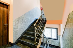 Una escalera con barandilla de metal y un extintor fijado a la pared.