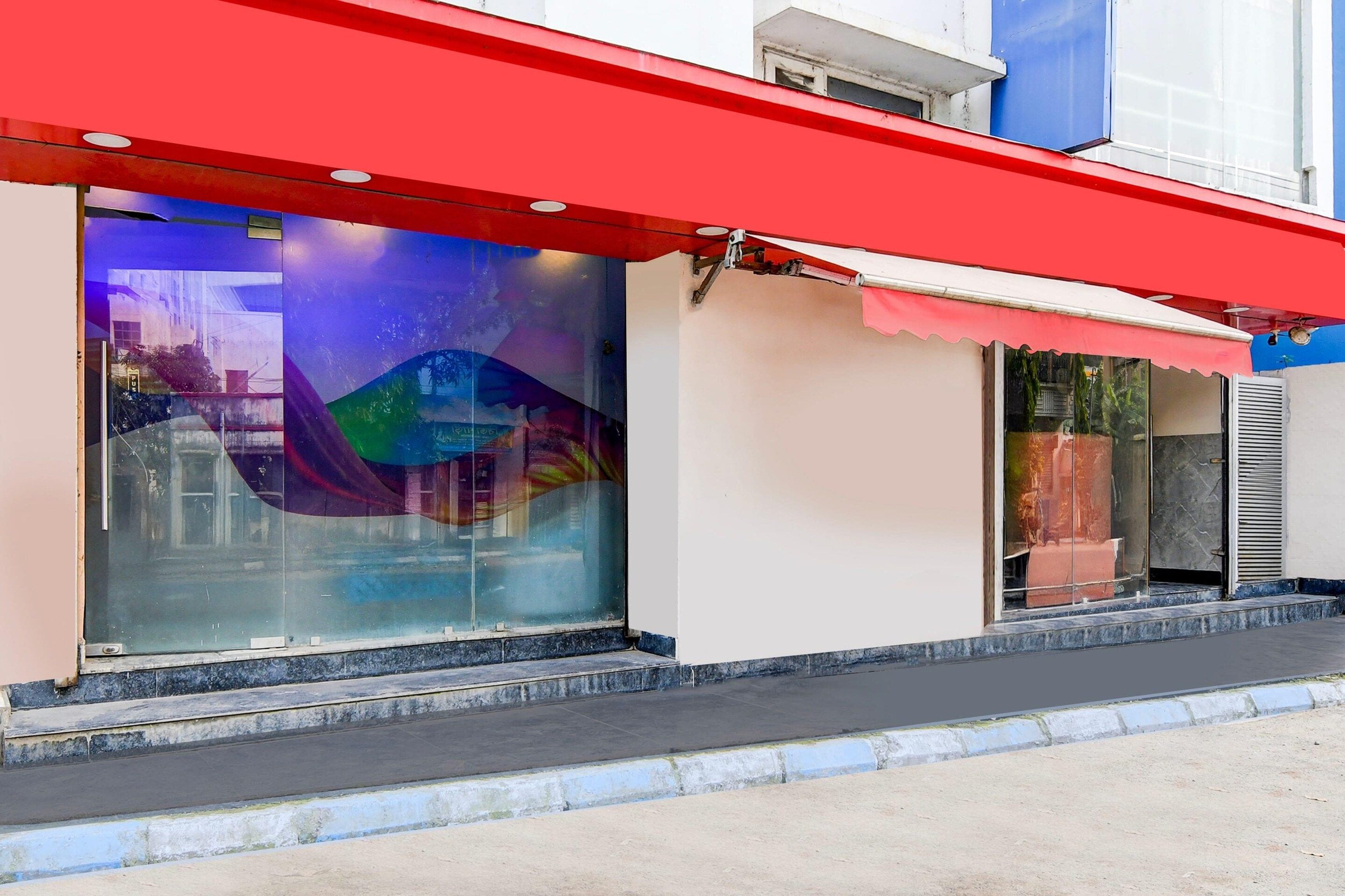 A building with a red awning and large glass windows reflecting a colorful mural.