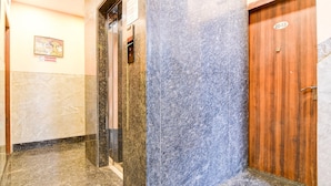 A hallway with a wooden door, a marble wall, and a no-smoking sign. - Deluxe Room Aspiring Inn (Kolkata)