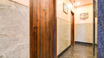 A hallway with wooden doors, marble walls, and a no-smoking sign.