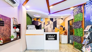 A reception area with a modern design, including a reception desk, a clock, and a wall with geometric patterns. - Deluxe Room Aspiring Inn (Kolkata)