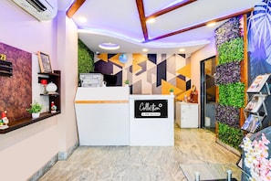 Et moderne receptionsområde med reception, et ur og en væg med geometriske mønstre.