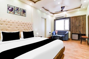 Una habitación de hotel con una cama grande, un sofá, un escritorio y un armario.