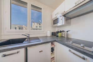 A modern kitchen with a built-in microwave, a sink, and a window with a view of buildings.
