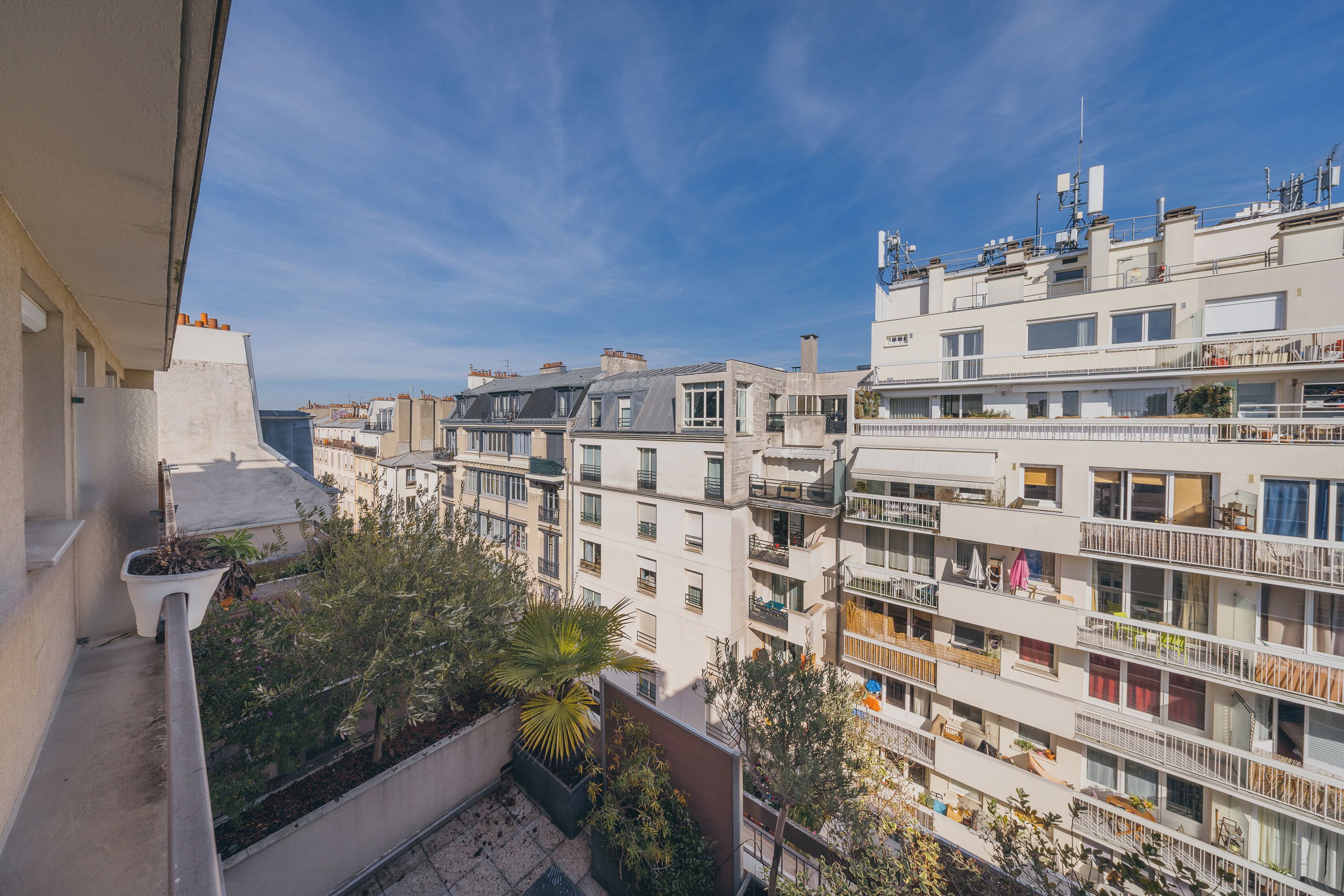 Un immeuble résidentiel à plusieurs étages, doté de balcons, avec un ciel dégagé et une vue sur le quartier environnant.