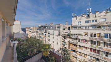 Un immeuble résidentiel à plusieurs étages, doté de balcons, avec un ciel dégagé et une vue sur le quartier environnant.