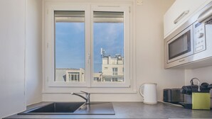 Una cocina compacta con ventana, un fregadero, un microondas y un refrigerador pequeño.