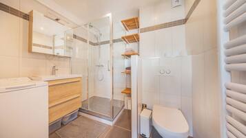A modern bathroom with a glass-enclosed shower, a wooden vanity, a toilet, and a towel rack.