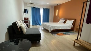 Ein Hotelzimmer mit Bett, Sofa, kleinem Tisch und Fernseher.