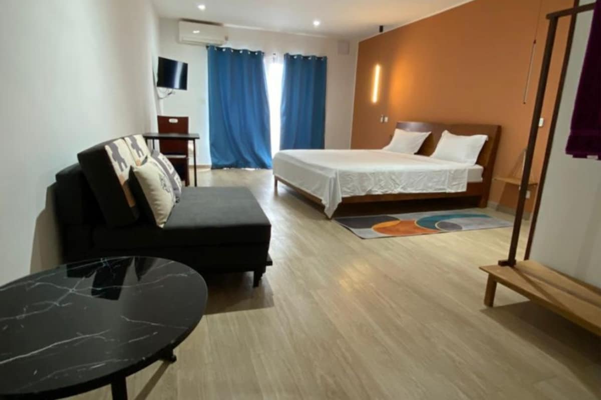 Ein Hotelzimmer mit Bett, Sofa, kleinem Tisch und Fernseher.