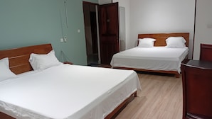 Quarto de hotel com duas camas, cabeceiras de madeira e uma escrivaninha de madeira.