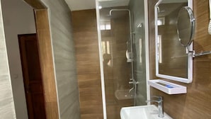 Ein modernes Badezimmer mit einer gläsernen Duschkabine, einem weißen Waschbecken und einem Spiegel.
