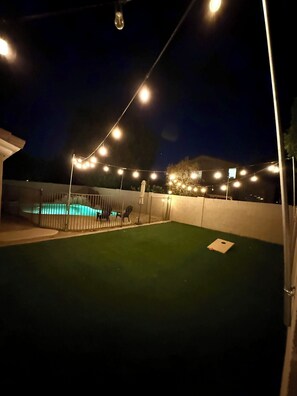 A nighttime outdoor area with artificial lighting, a swimming pool, and a fenced enclosure. - Spacious Peoria retreat with private pool, 5 bedrooms & family fun! (Peoria)
