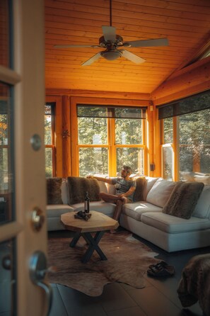 A room with a white sofa, a wooden coffee table, and a ceiling fan. - Luxury log cabin 1 hour from Montreal (Mille-Isles)