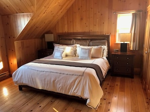 A wooden-paneled bedroom with a bed, nightstands, and a window. - Luxury log cabin 1 hour from Montreal (Mille-Isles)