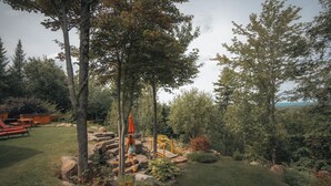 A landscaped garden with a wooden deck, picnic tables, and a stone pathway.
