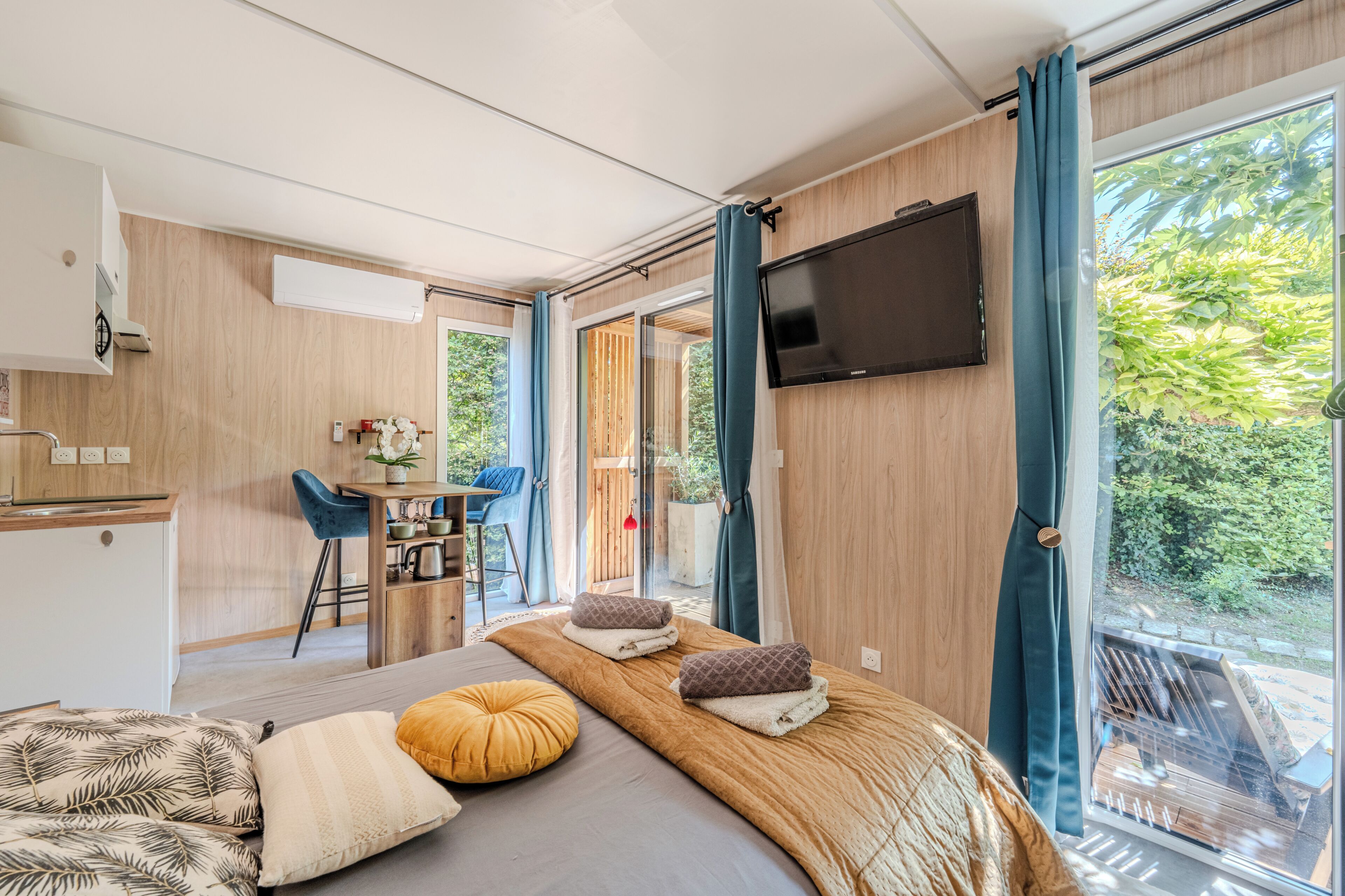 Een moderne slaapkamer met een bed, een televisie, een bureau en uitzicht op het omliggende landschap.