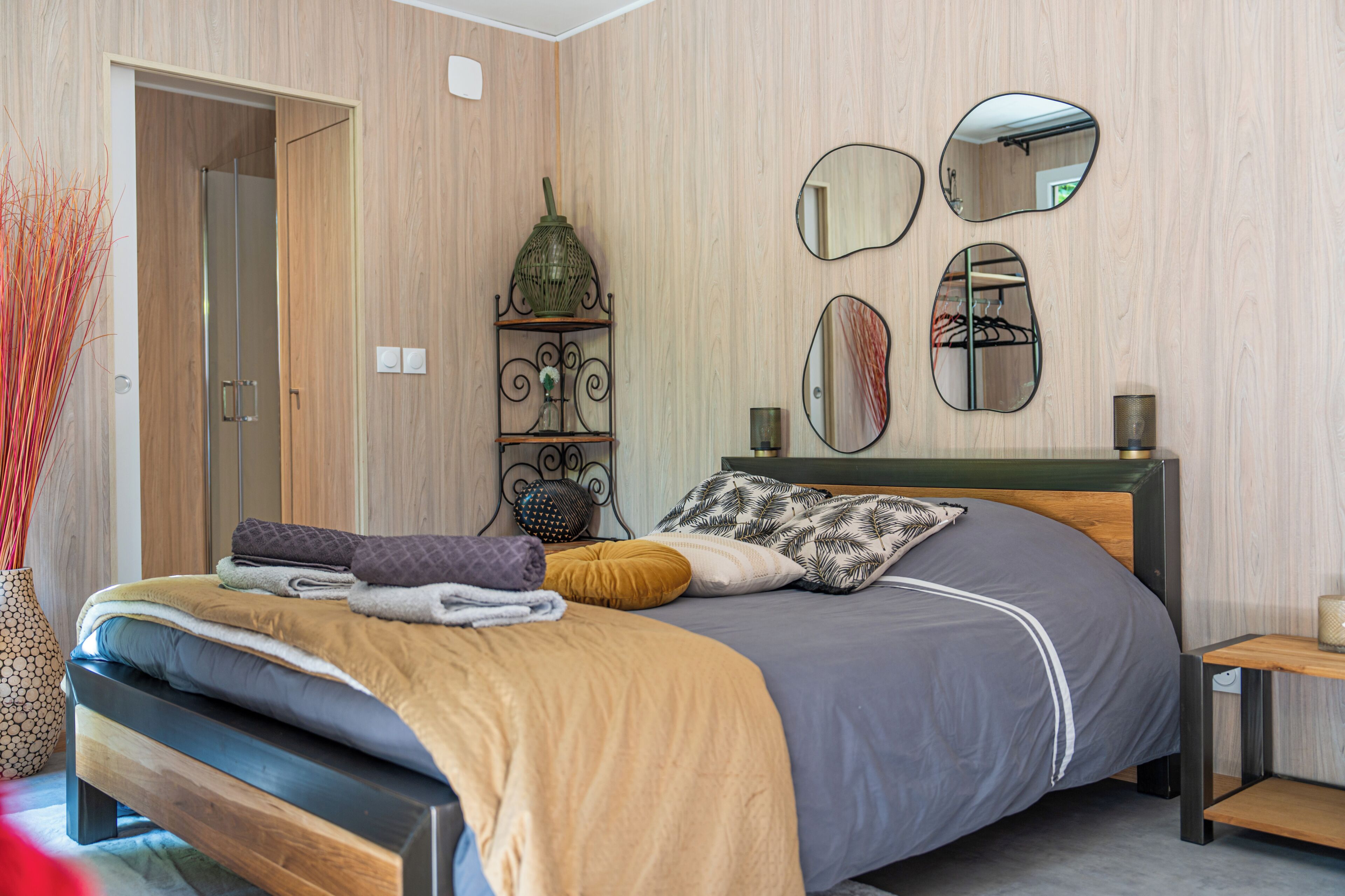 Un dormitorio moderno con una cama, mesitas de noche y espejos fijos en la pared.