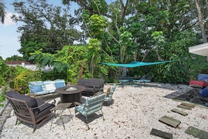 An outdoor patio area with a round table, two sofas, and a dining set.