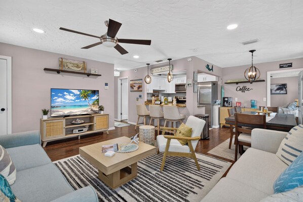 A modern living room with a television, sofa, coffee table, and a ceiling fan.