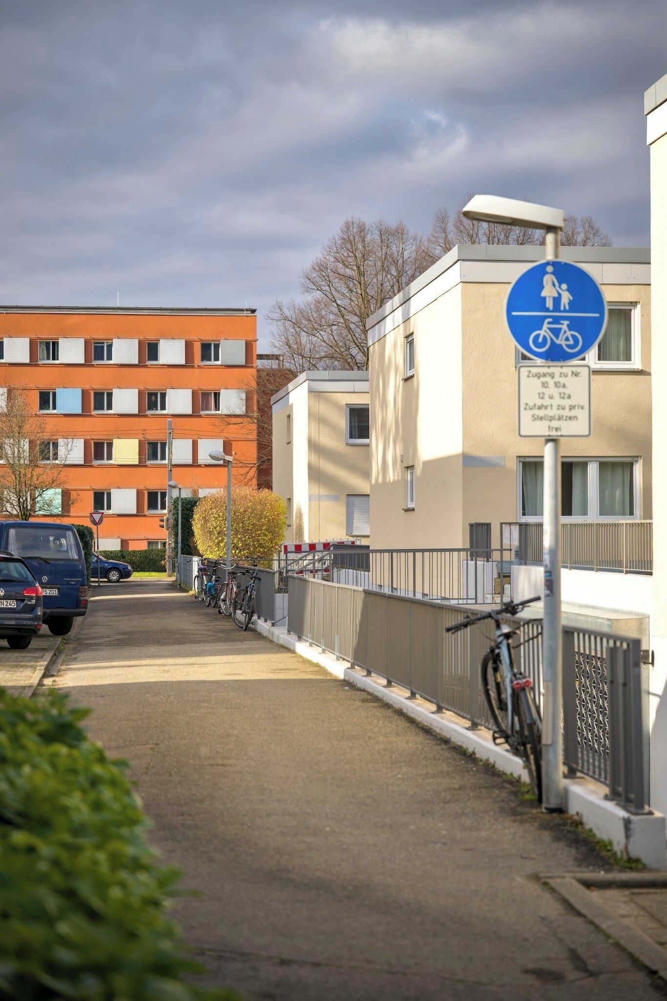 Eine Wohnstraße mit einem blauen Schild, das einen Parkbereich für Kinder und Fahrräder kennzeichnet.