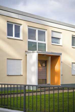 Un edificio con facciata beige, diverse finestre e un ingresso carrabile.