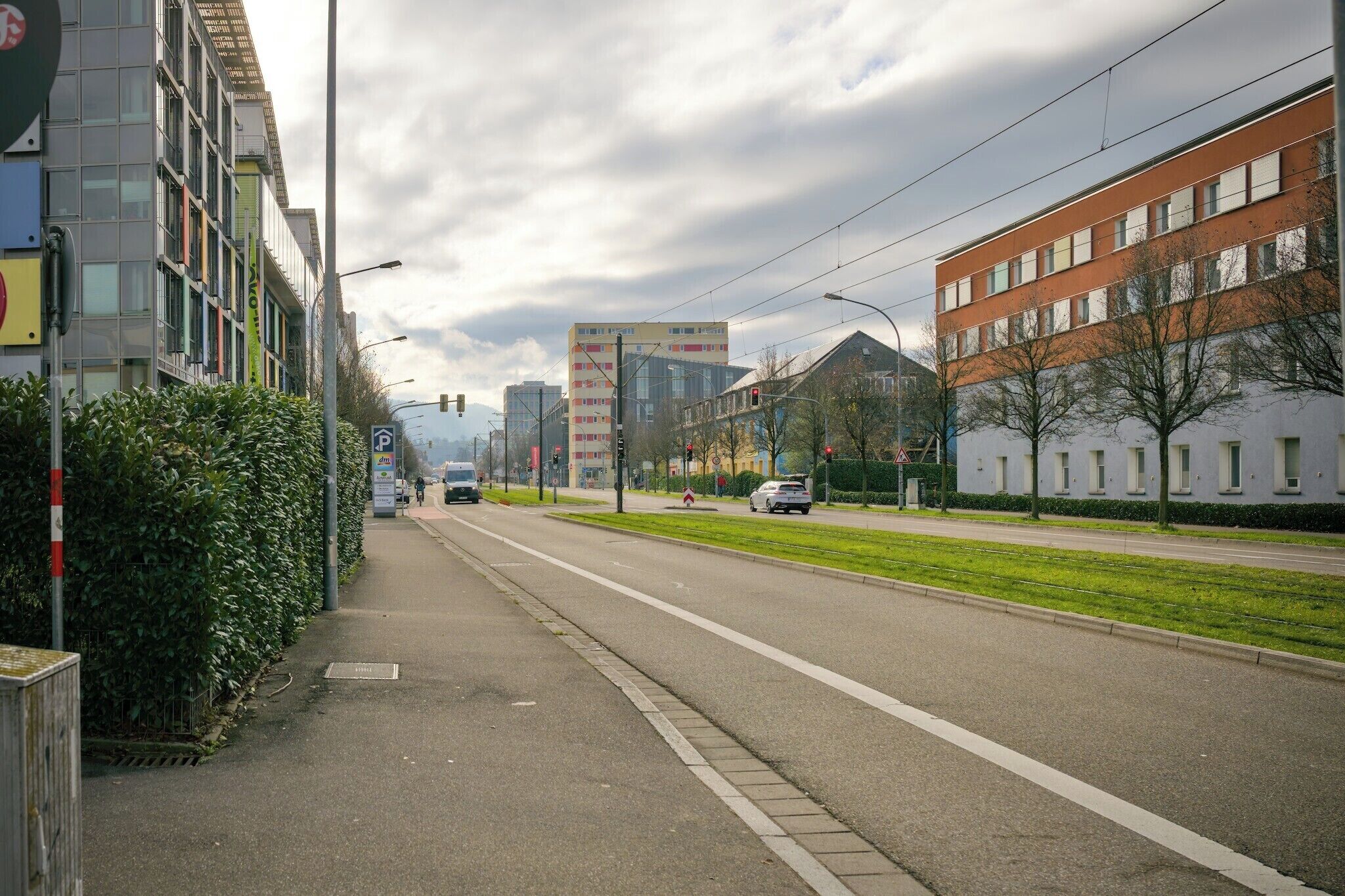 Uma rua urbana com edifícios, uma calçada e veículos.